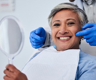 Woman smiling while holding small mirror