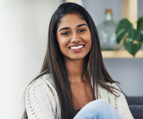 a teen smiling and sitting on a couch