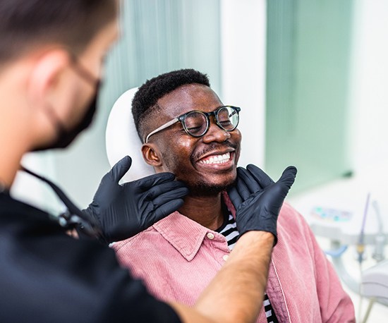 Dentist looking at patient’s smile in treatment room