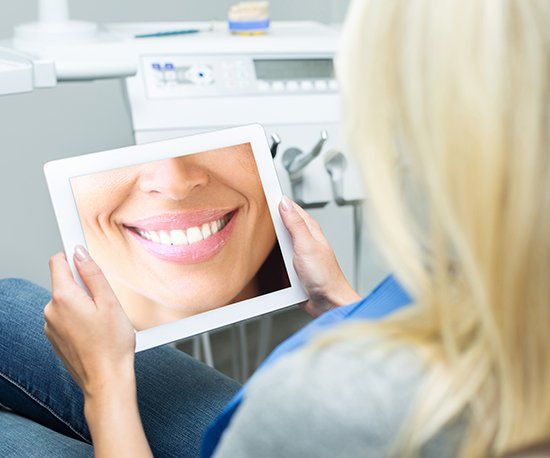 Woman looking at smile design on tablet computer