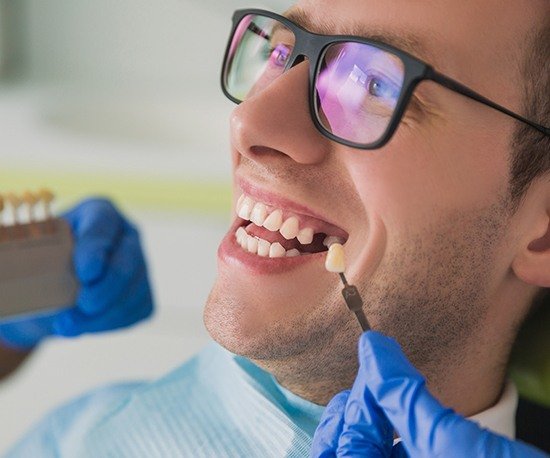 Man's smile compared with tooth color chart