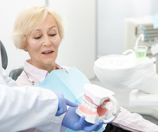 dentist showing a denture model to a patient 