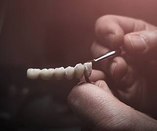 Lab technician painting replacement teeth