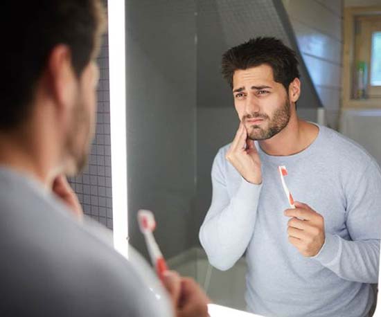 Man with a dental emergency in Murphy holding a toothbrush