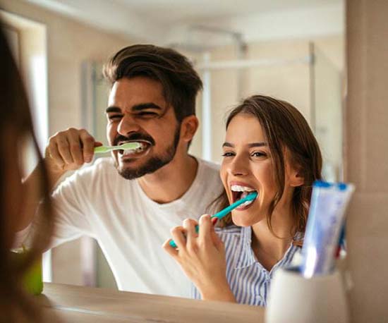 Couple preventing dental emergencies in Murphy by brushing