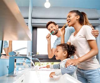 Family in front of mirror, brushing teeth together