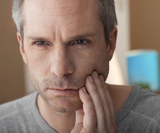 Man in pain holding cheek