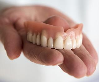 Hand holding a full denture