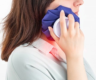a woman using a cold compress on her jaw