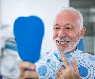 senior man admiring his new smile with dental implants in Murphy
