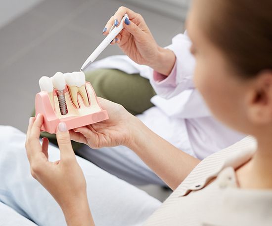 dentist showing a patient a model of how dental implants work 