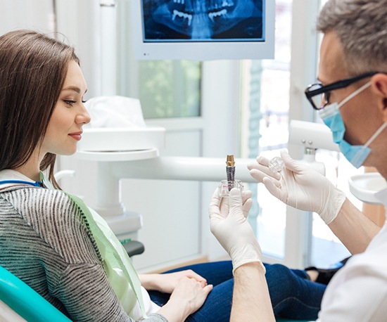 dentist showing a dental implant to a patient