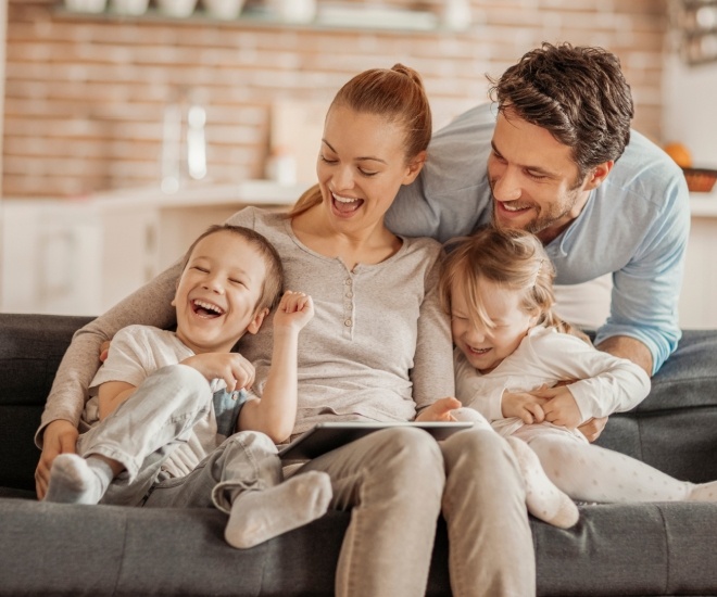 Laughing family of four sitting on couch