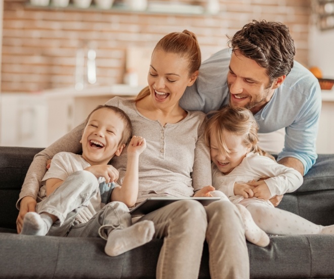 Laughing family of four sitting on couch