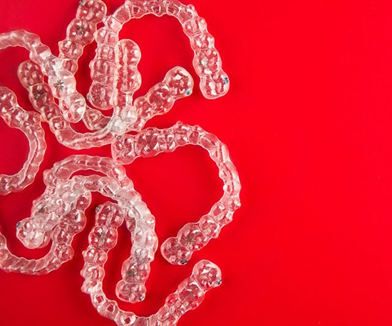 several clear aligners in front of a red background 