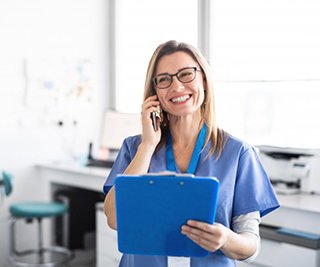 dental hygienist talking on the phone and holding a blue clipboard 