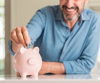 man putting coins into a pink piggy bank 