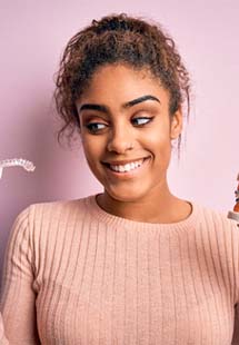 young woman looking at Invisalign and metal braces