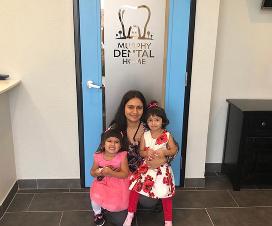 Dr. Gandhi and kids smiling in dental office