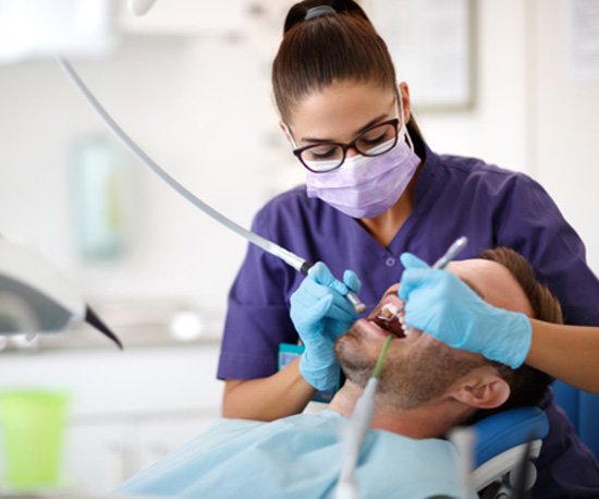 Dentist carefully performing treatment in patient’s mouth?