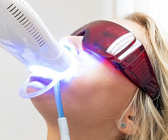 Woman receiving teeth whitening in dental office