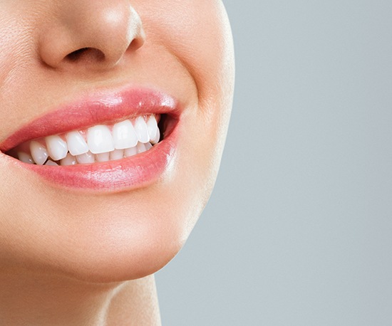 Nose-to-neck ¾ profile view of woman smiling with with teeth