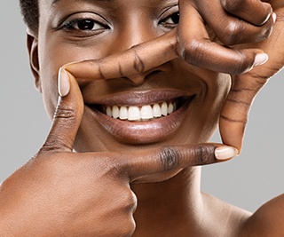 Woman framing bright white smile with 4 fingers