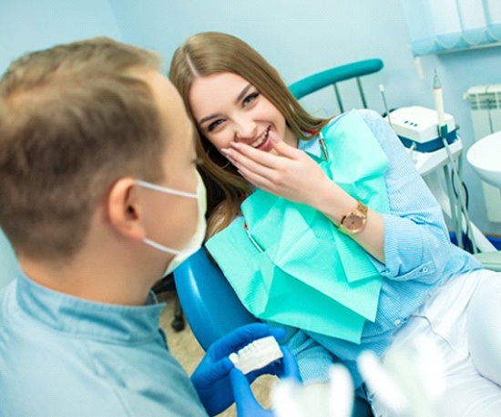 smiling young woman talking to her dentist in Murphy