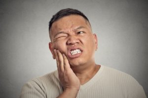 Pained man with hand on cheek needs to see Murphy emergency dentist