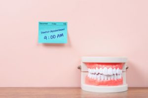 a sticky note with a dental checkup appointment reminder and a model of teeth next to it