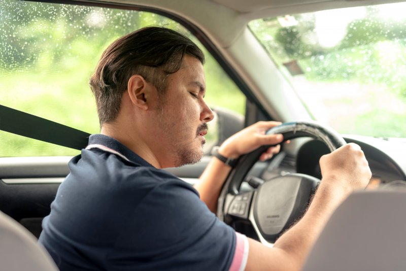 a man falling asleep behind the wheel