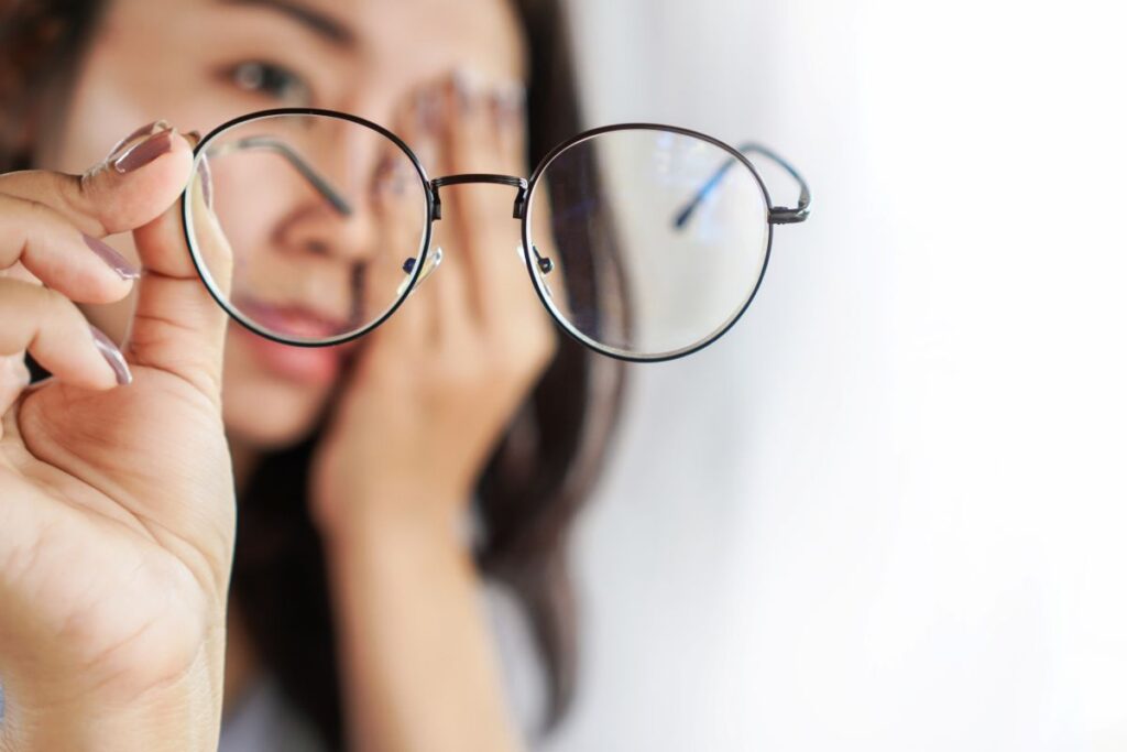 A woman holding a pair of eyeglasses