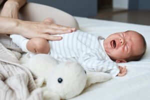 Baby lying on its back crying.