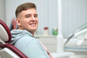 Smiling young man in dental treatment chair 